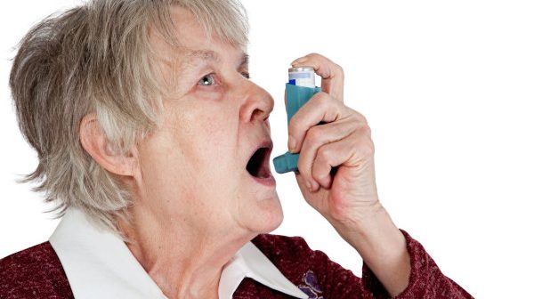 Senior woman spraying anti asthma on her mouth