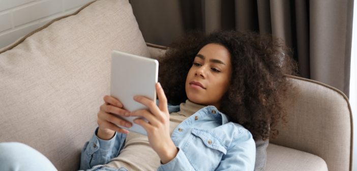 Young woman lying on the couch with her tablet